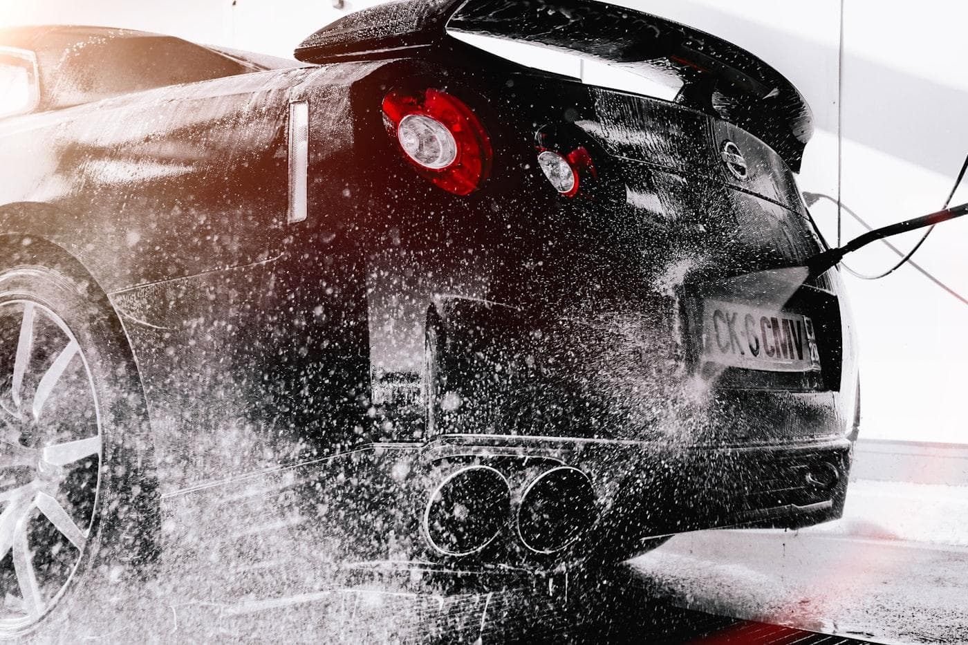 Car being rinsed with a pressure washer at a professional car wash